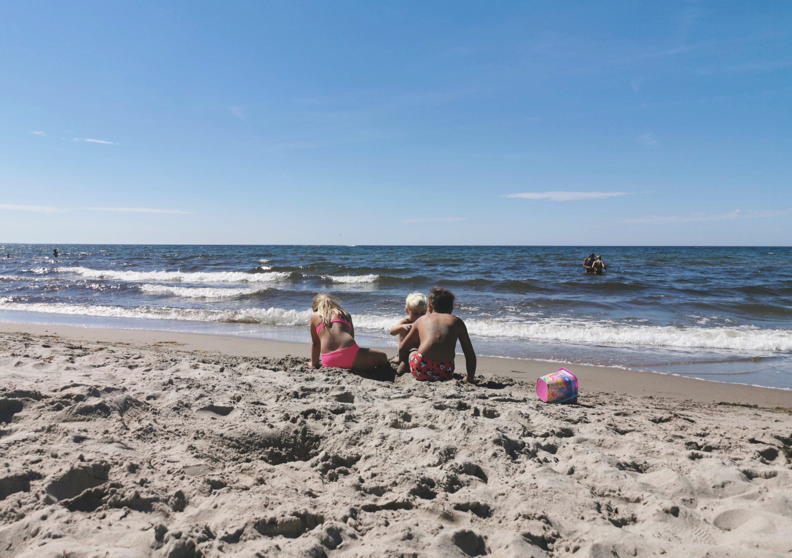 Tre barn leker på en sandstrand