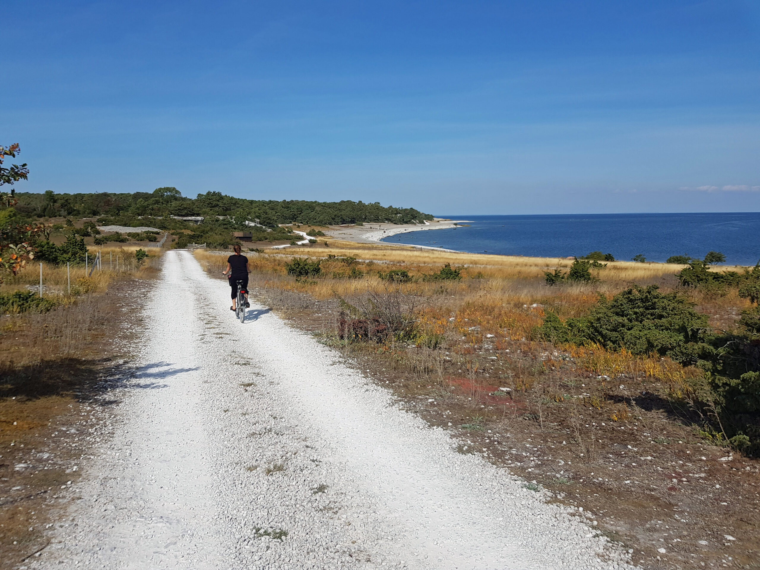 cyklande person på grusväg vid havet