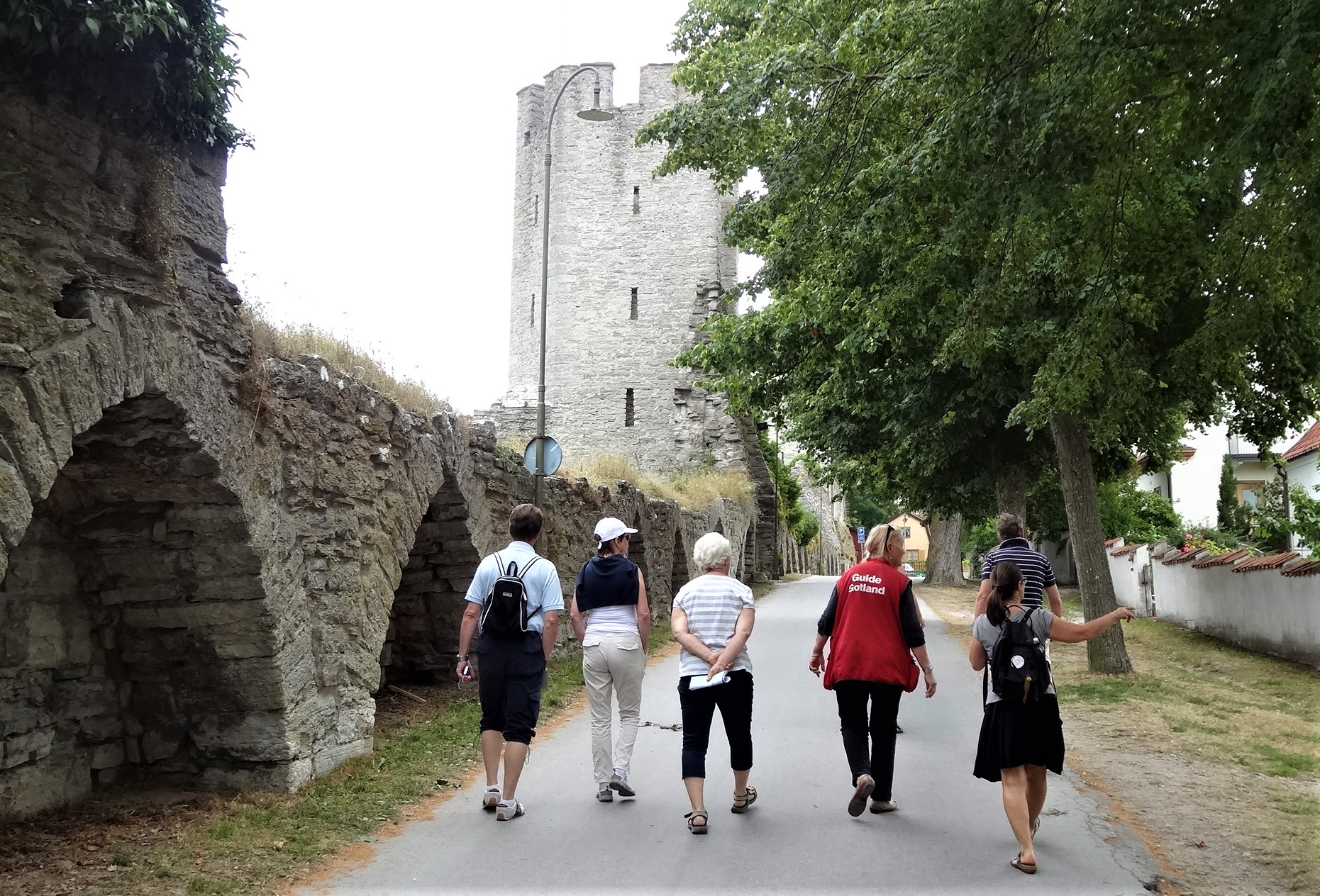 Personer går på guidad tur innanför ringmuren i Visby
