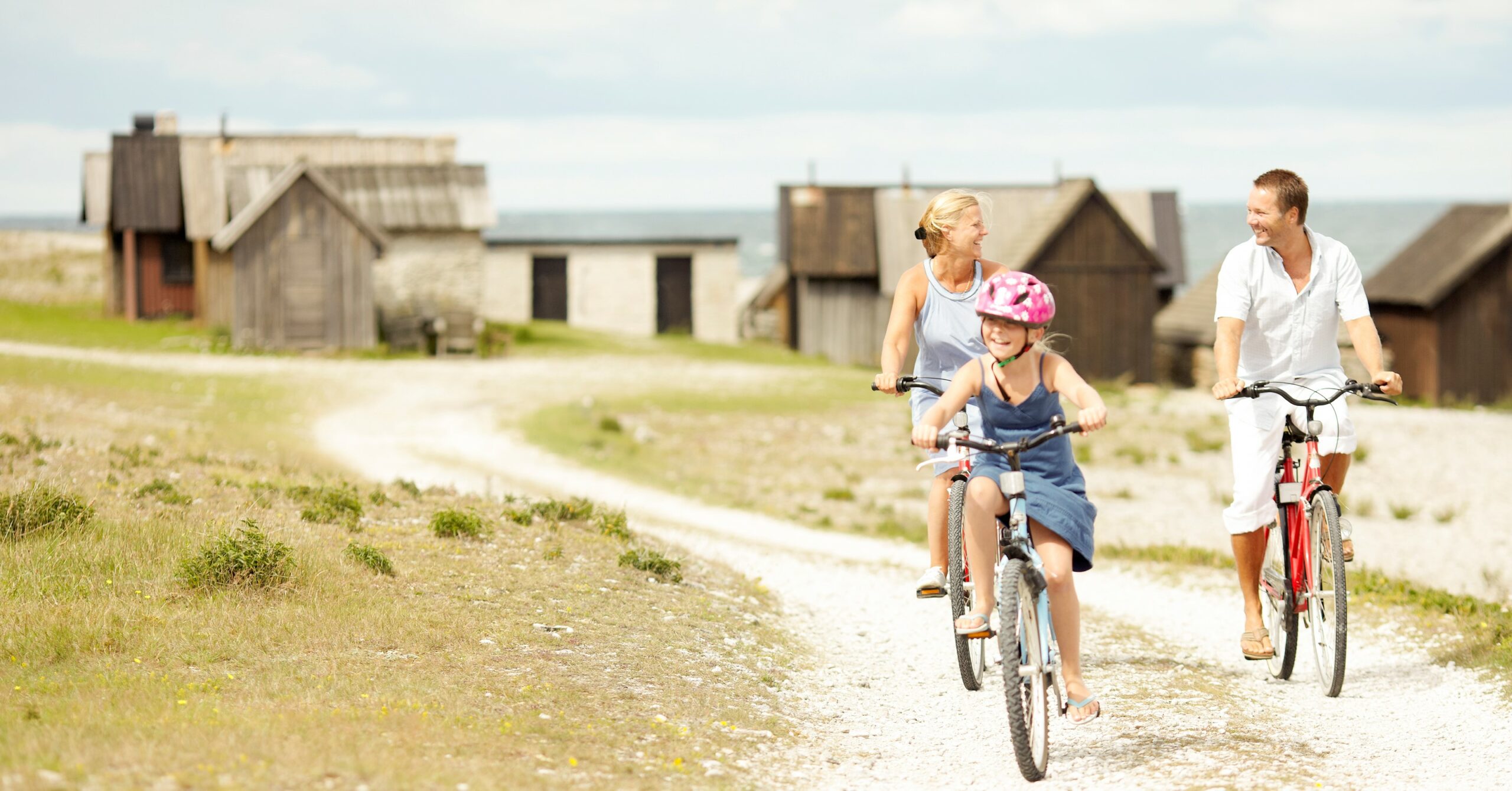 Familj cyklar vid fiskeläge på Gotland.