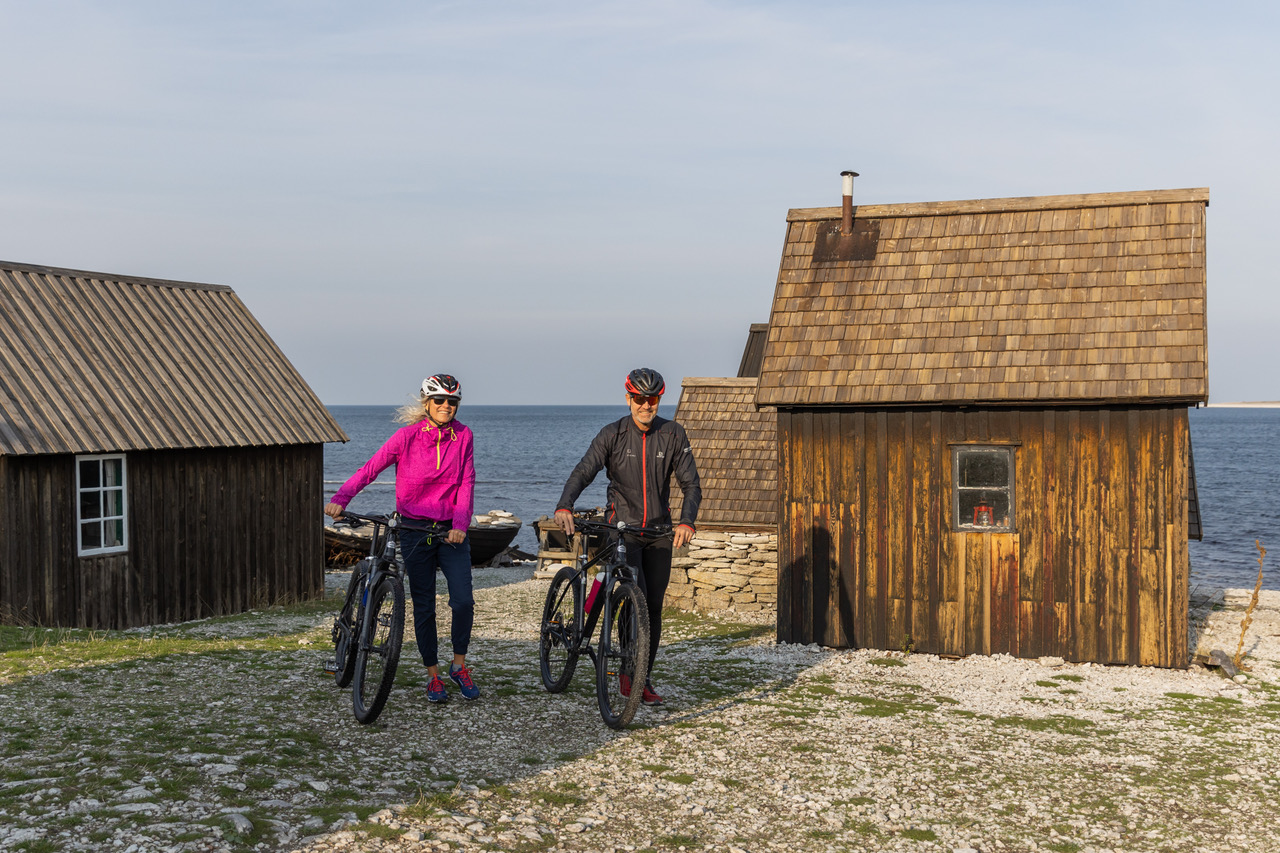 Par som står vid en fiskestuga med sina cyklar