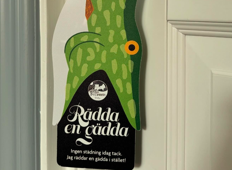 Rolig skylt man kan hänga på dörren om man vill ha hotellrummet städat. Skylten är i form av en gädda med texten 
